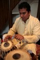 Udit Pankhania tunes his Tabla. The skin is tensioned by a number of cords that run down the sides; inside each pair of cords is a large wooden toggle. The further down the barrel of the drum the toggle is moved, the tighter the skin is made, raising the pitch.\n\nThe black circles in the middle of each drum skin, which enable an even wider variety of sounds to be made, are built up in layers of rice starch mixed with coal dust.