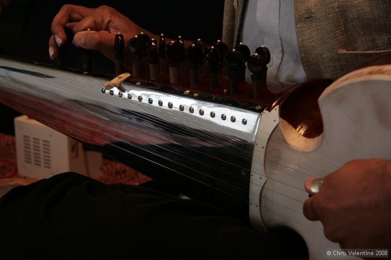 Tarun Jasani tunes his Sarod. As you can see, the fingerboard has no frets and the strings are metal wire, not synthetic, but the player only uses his fingers, not a slide - I imagine it can be painful when you're just learning!